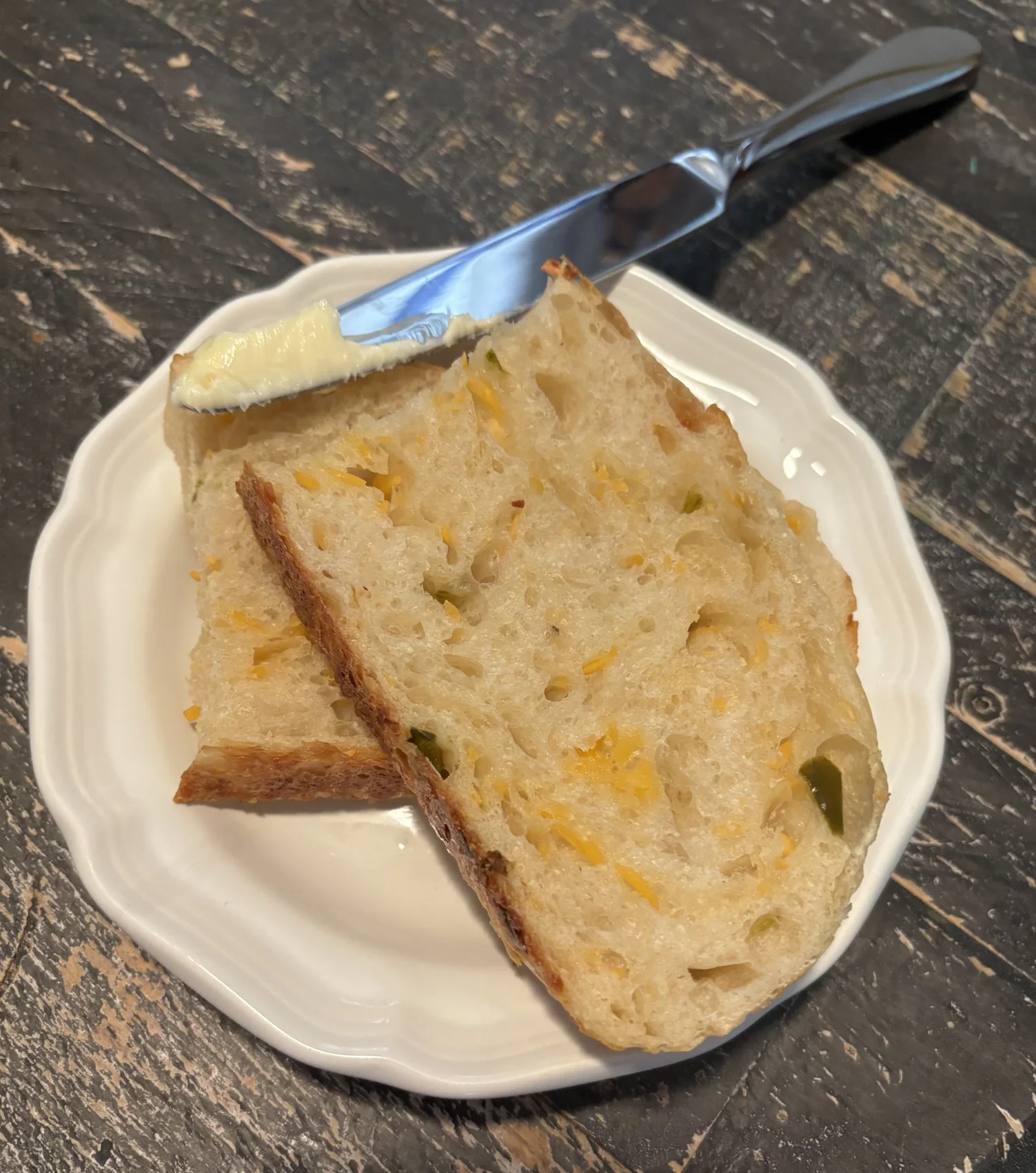Slices of jalapeño cheddar sourdough bread served with butter on a white plate