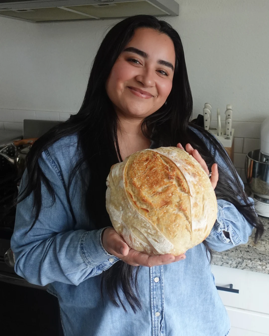 Jessica Macias, the baker behind Five Loaves Sourdough in Stockton, California, holding a fresh sourdough loaf